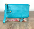 Turquoise HOBO Evolve leather wristlet clutch with gold hardware and detachable strap shown next to Canadian $50 bill for size reference.