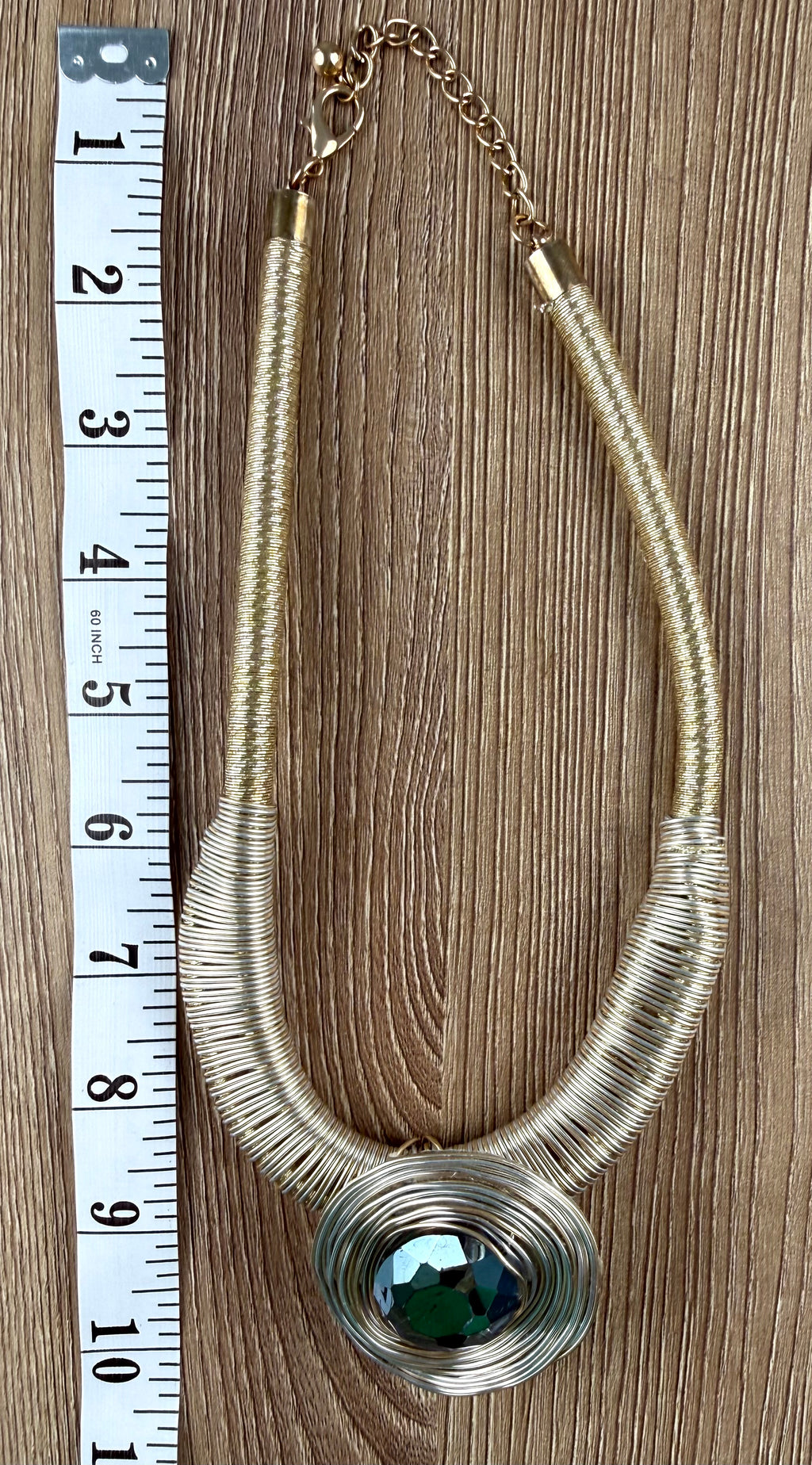 Gold-tone wire coil statement necklace with dark green faceted crystal pendant, laid flat with measuring tape, full length view — Blue Sparrow pre-loved jewellery