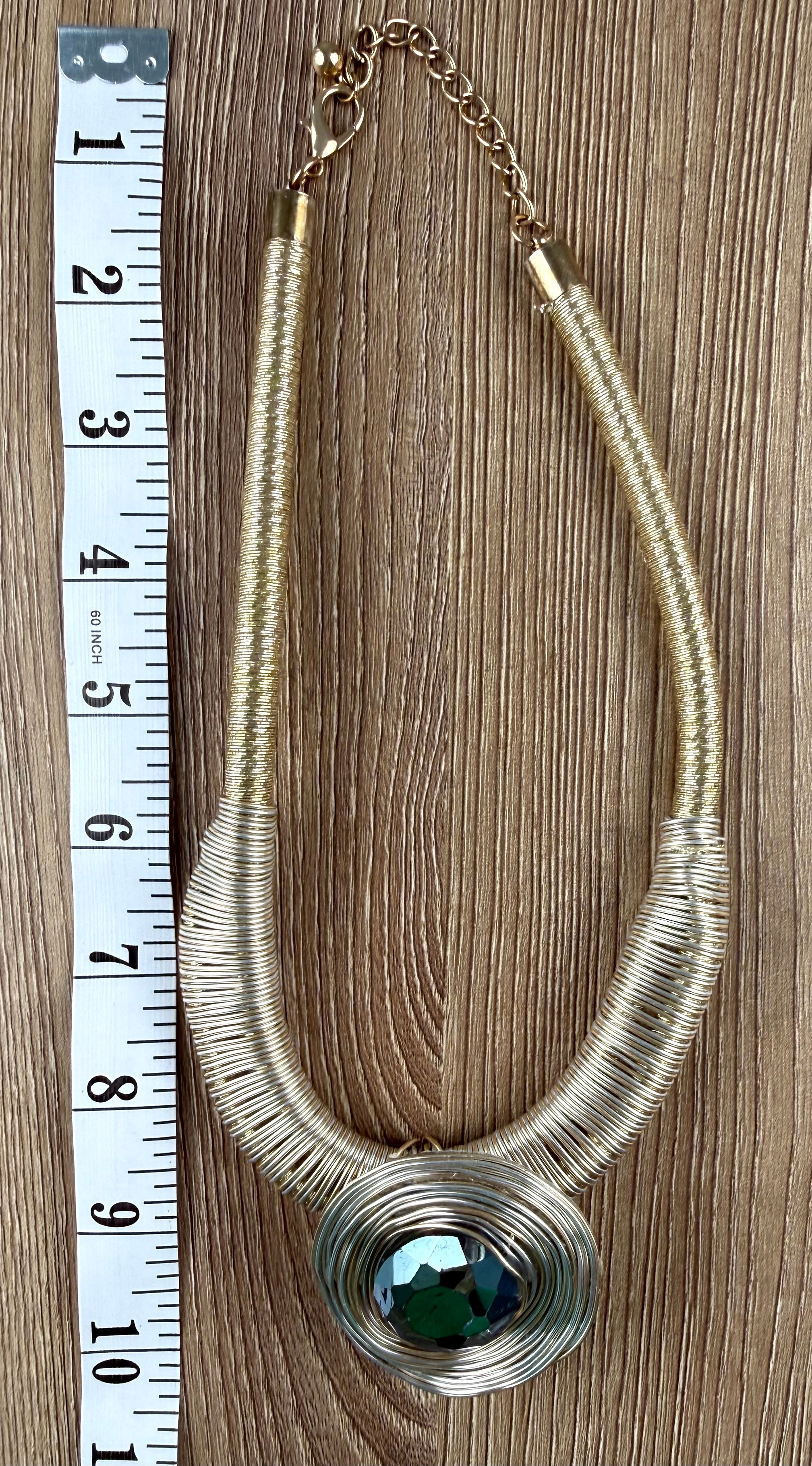 Gold-tone wire coil statement necklace with dark green faceted crystal pendant, laid flat with measuring tape, full length view — Blue Sparrow pre-loved jewellery