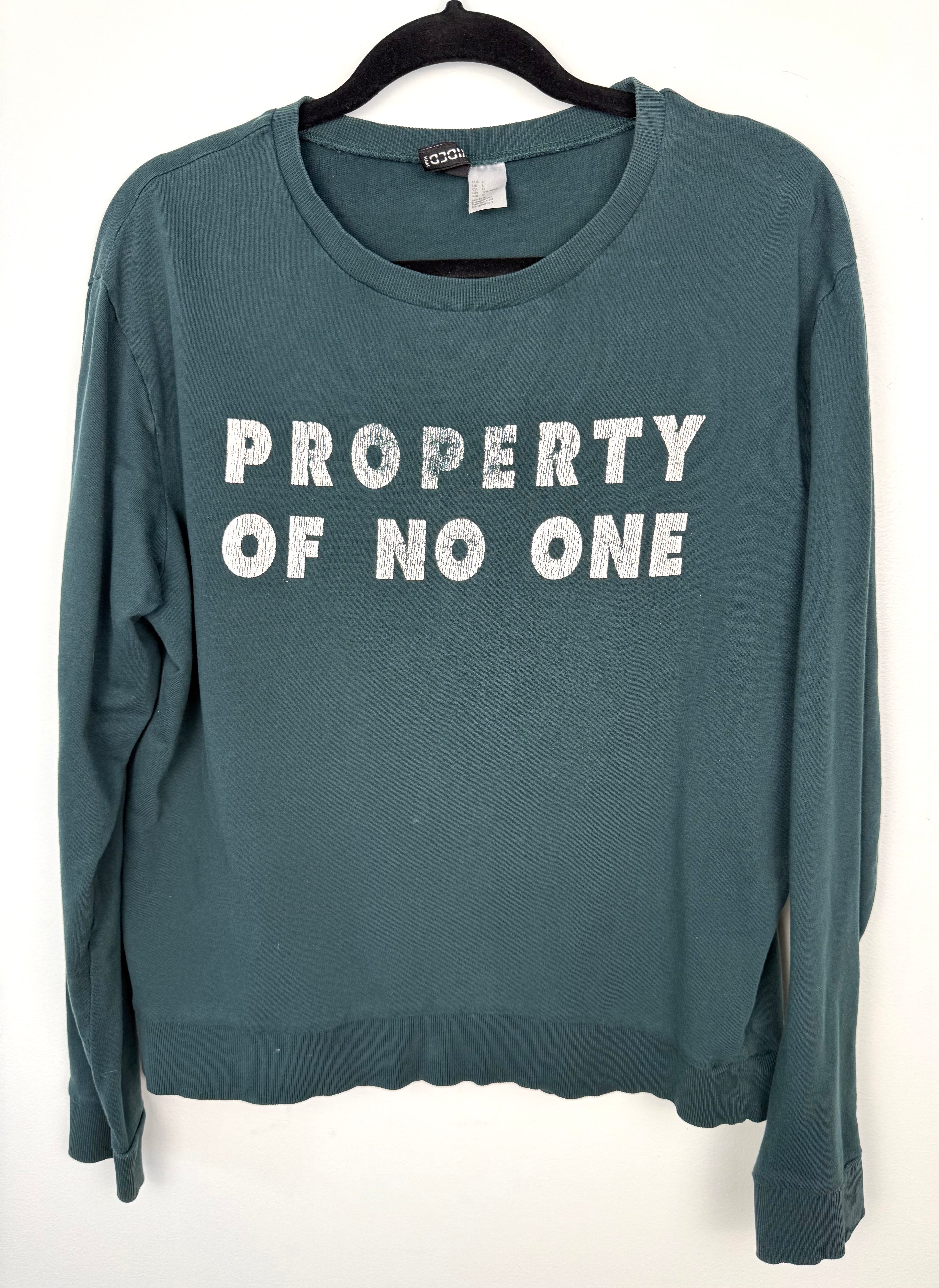 H&M Divided teal green 100% cotton graphic crew neck sweatshirt with "Property of No One" distressed white lettering, front view on hanger — Blue Sparrow pre-loved women's fashion front view on hanger