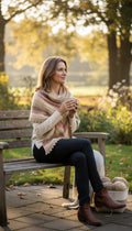 Handknit artisan cottagecore triangle shawl neutral sand cream blush stripe scalloped edge — new — Blue Sparrow women's accessories on woman outside on park bench