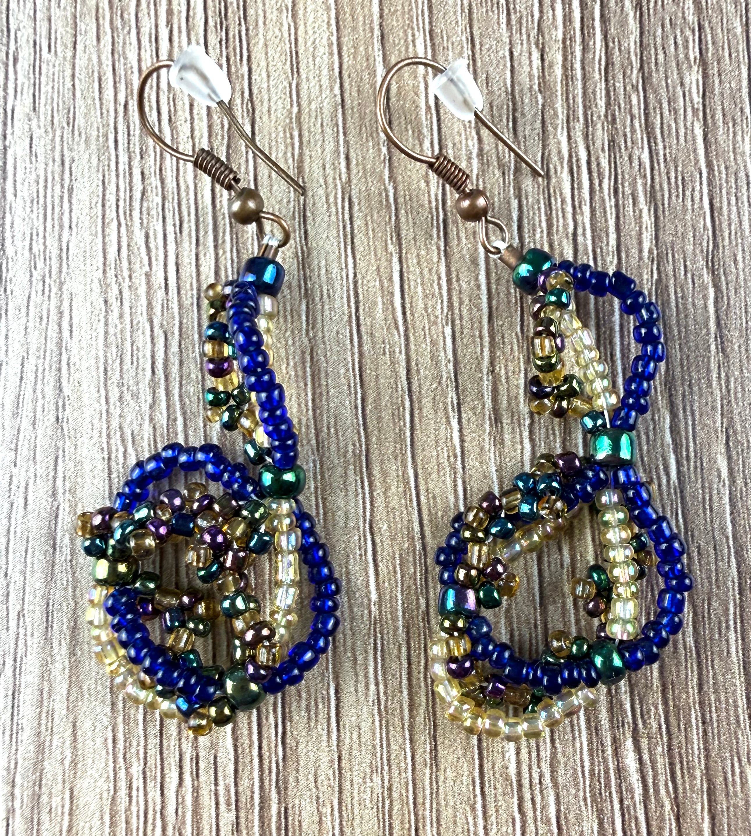 Handmade Seed Bead Dangle Earrings in blue and gold on table 