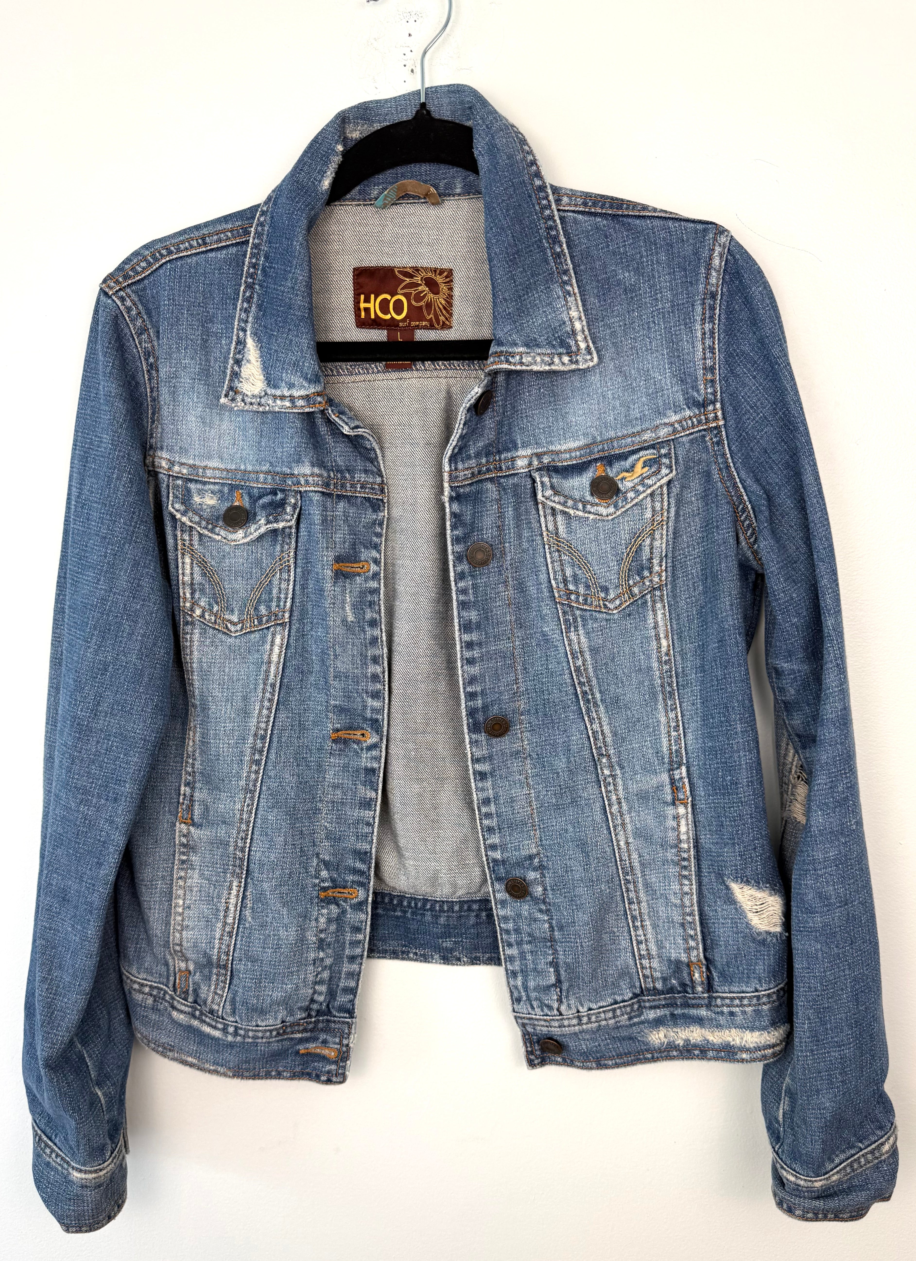 Hollister HCO 100% Cotton Distressed Trucker Denim Jacket — Medium Wash | Size L at Blue Sparrow Shop on hanger