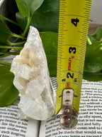 Apophyllite  with a measuring tape on top of a book with green leaves in the background