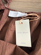 Close-up of a brown garment with Aritzia and Little Moon labels on a wooden surface.