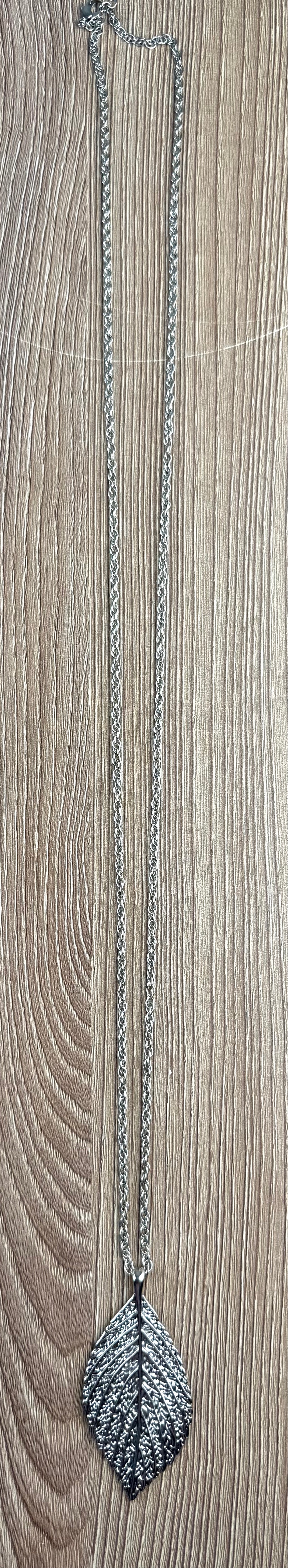 Long Silver Leaf Pendant Necklace on table
