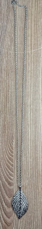 Long Silver Leaf Pendant Necklace on table