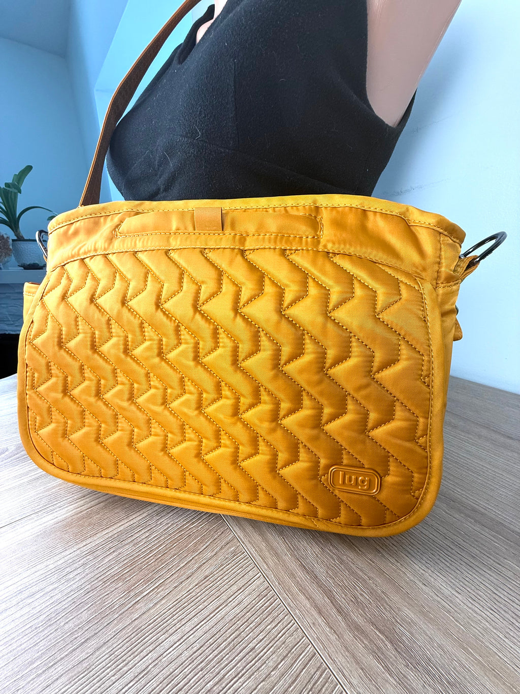 Lug crossbody travel bag in mustard yellow on mannequin side view