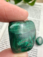 Green malachite stone held between fingers with a blurred background