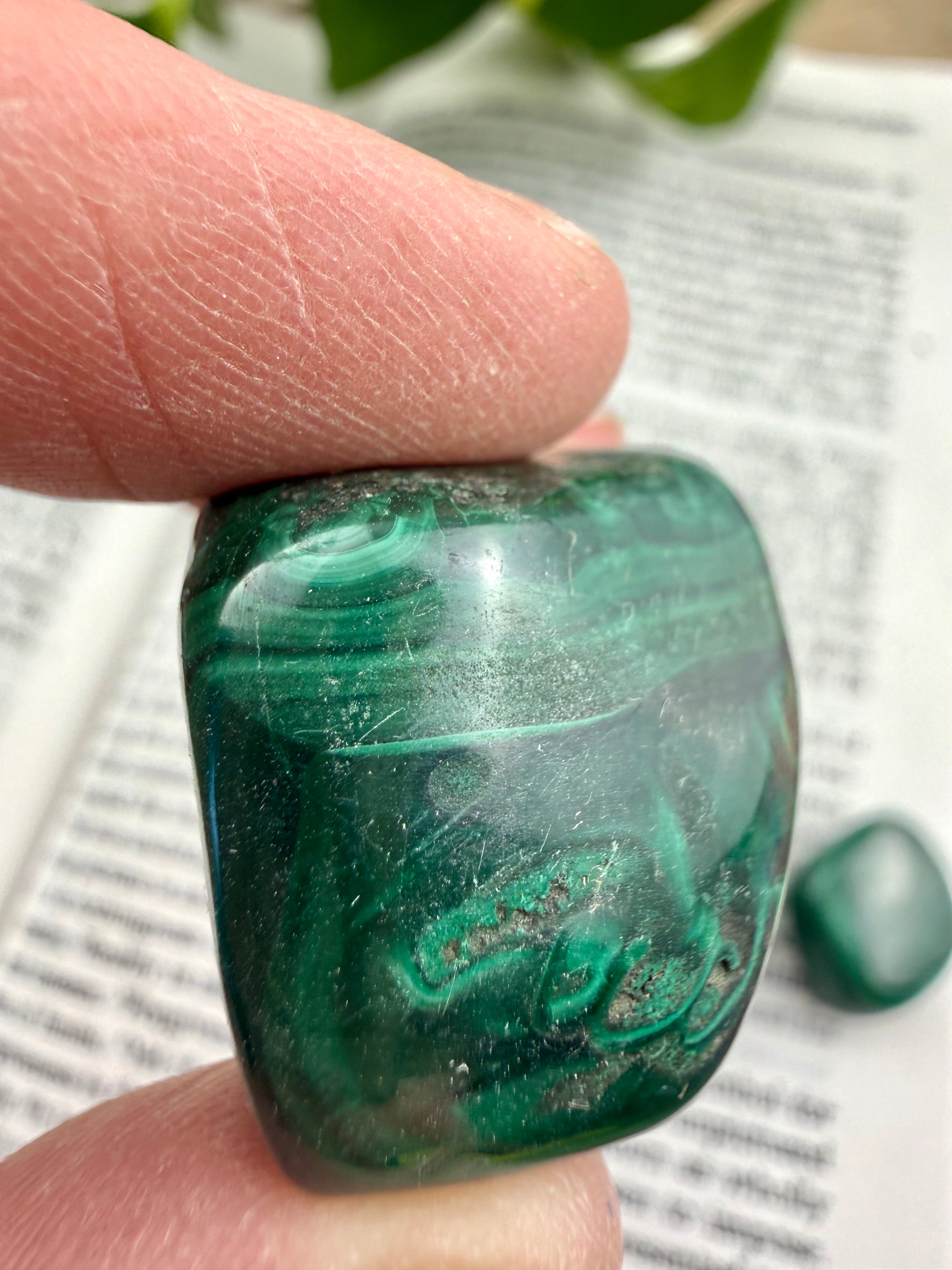 Green malachite stone held between fingers with a blurred background