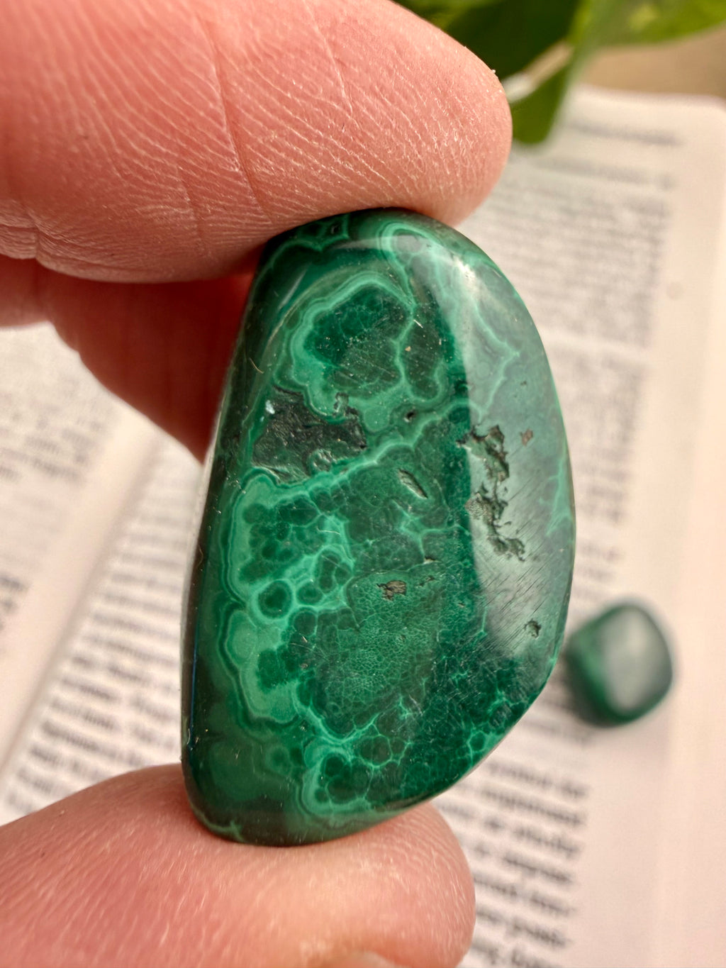 Greenish-blue stone held between fingers on a paper background