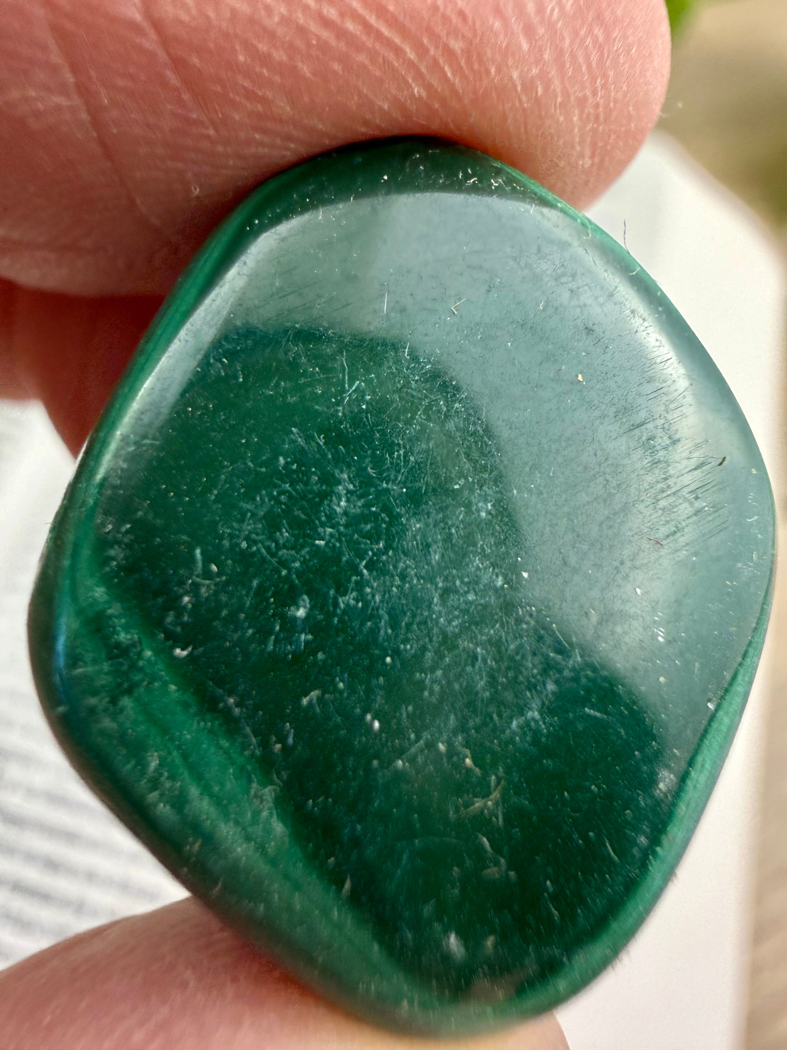 Green stone held between fingers with a blurred background