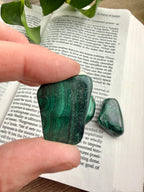 Green malachite stone held over an open book
