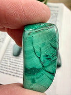 Green mineral stone held between fingers with a blurred background