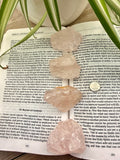 Open book with a pink crystal and green leaves on a wooden surface