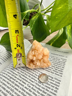 Stilbite Geode crystal on an open book with a measuring tape for scale