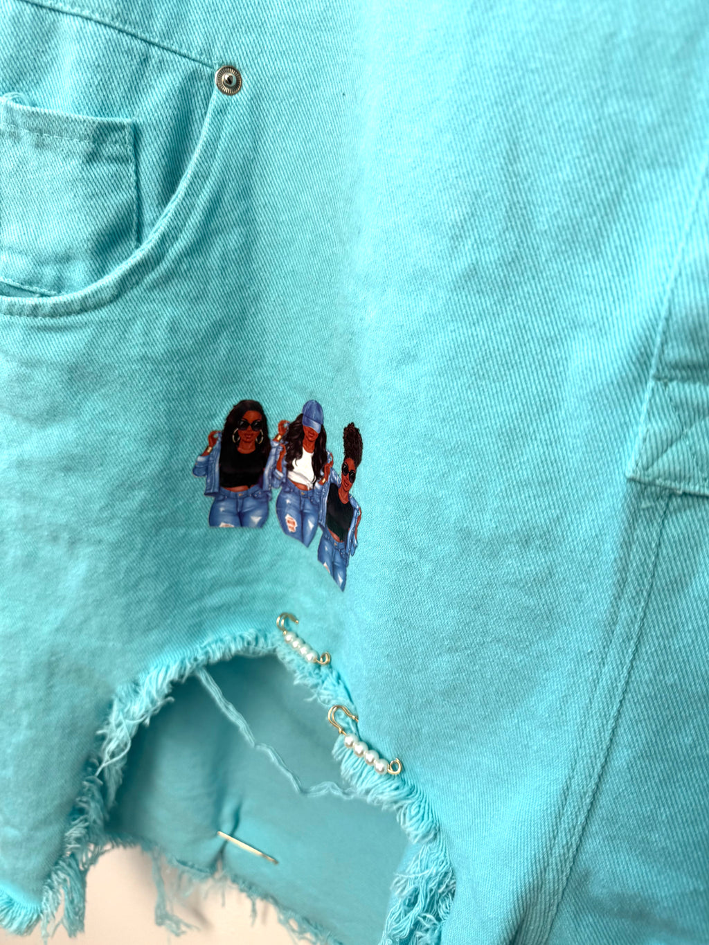 Oversized Turquoise denim romper close up of hem with fun detail and decals