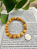 Wooden beaded bracelet on an open book with a coin for size reference