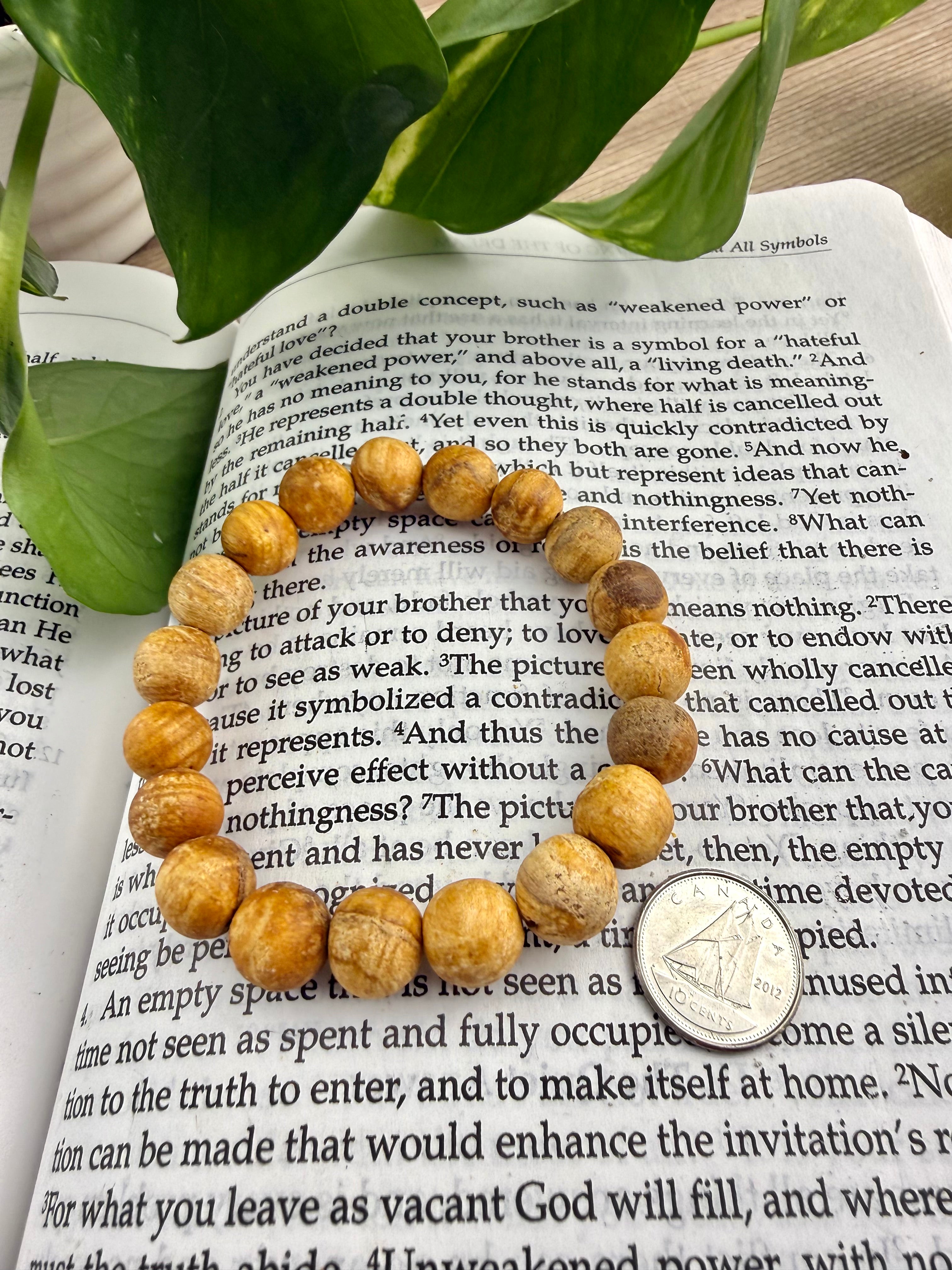 Wooden beaded bracelet on an open book with a coin for size reference