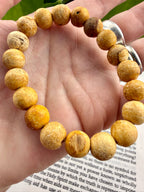 Hand wearing a bracelet with yellow-beige beads on a book page background