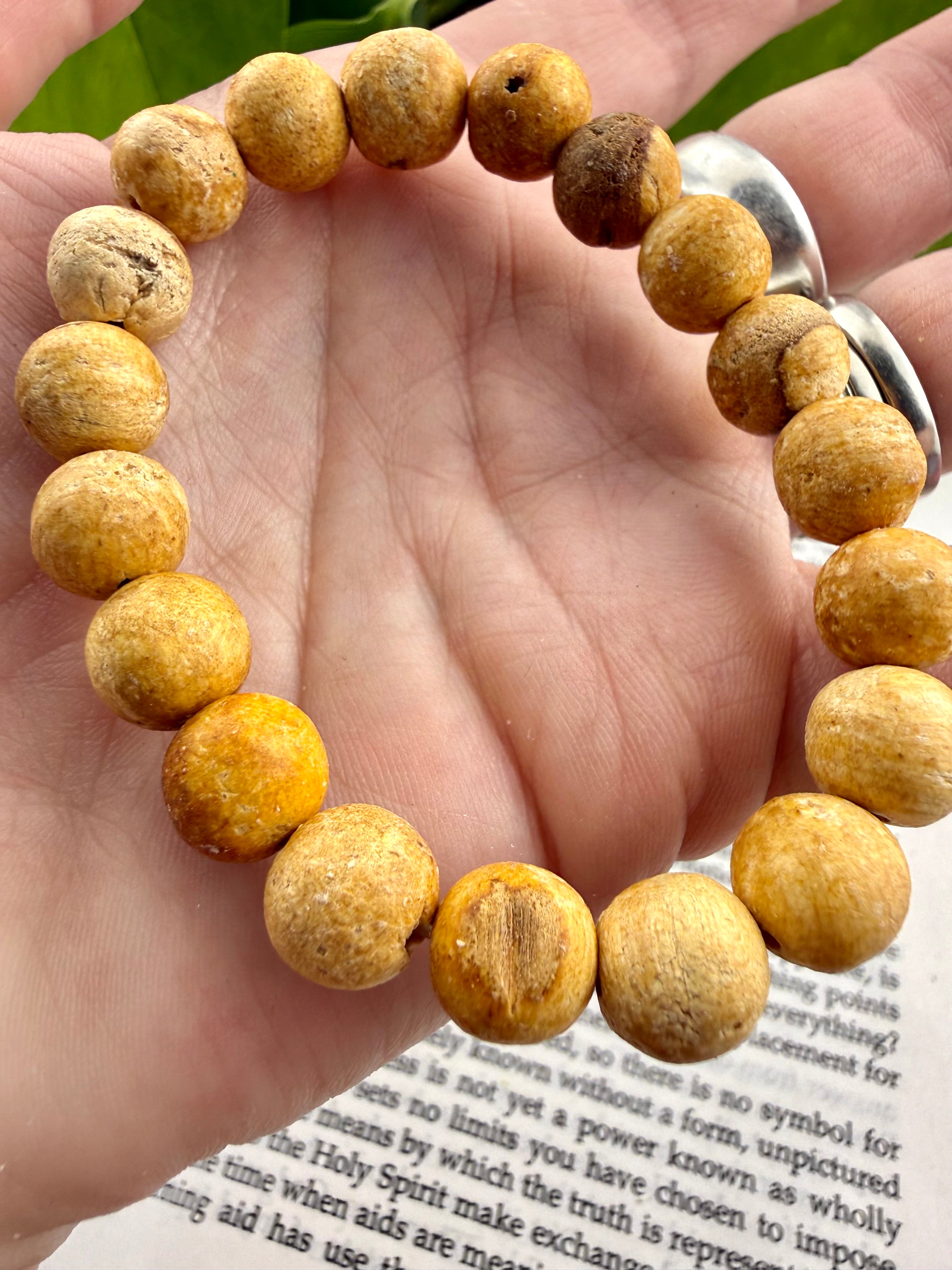 Hand wearing a bracelet with yellow-beige beads on a book page background