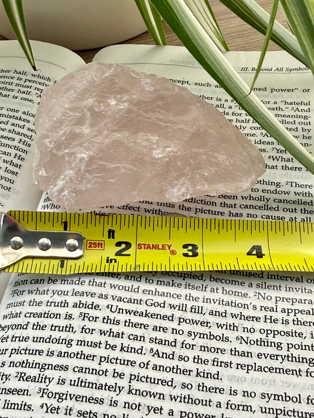 Raw crystal rock on top of a book with a measuring tape for scale