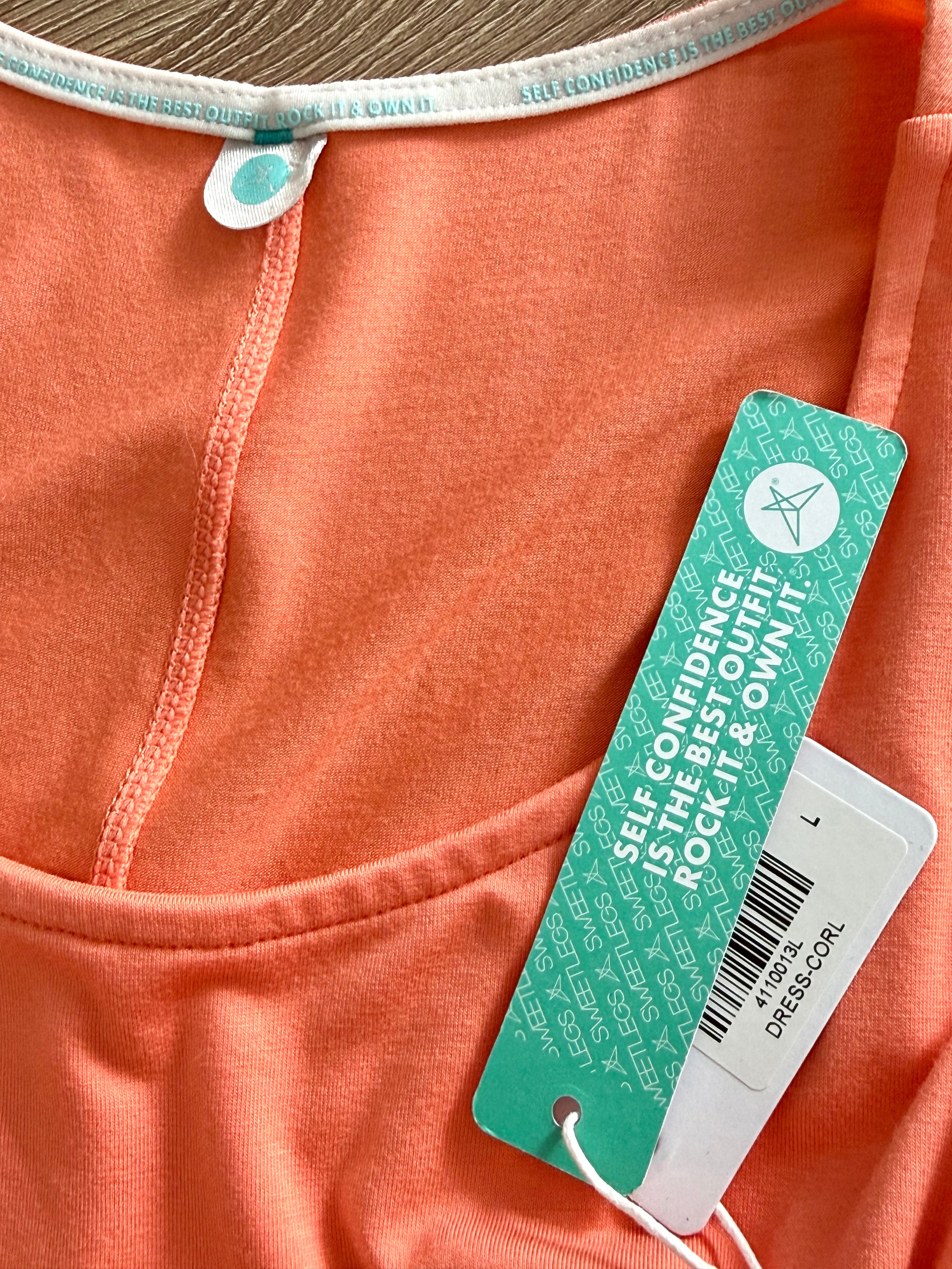 Close-up of a NWT coral coloured dress with a green and white tag.
