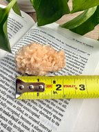 Stilbite crystal on an open book with a measuring tape for scale