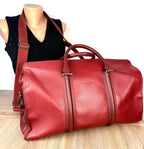 Ted Baker London red pebbled leather weekender duffel bag with adjustable shoulder strap displayed on mannequin.