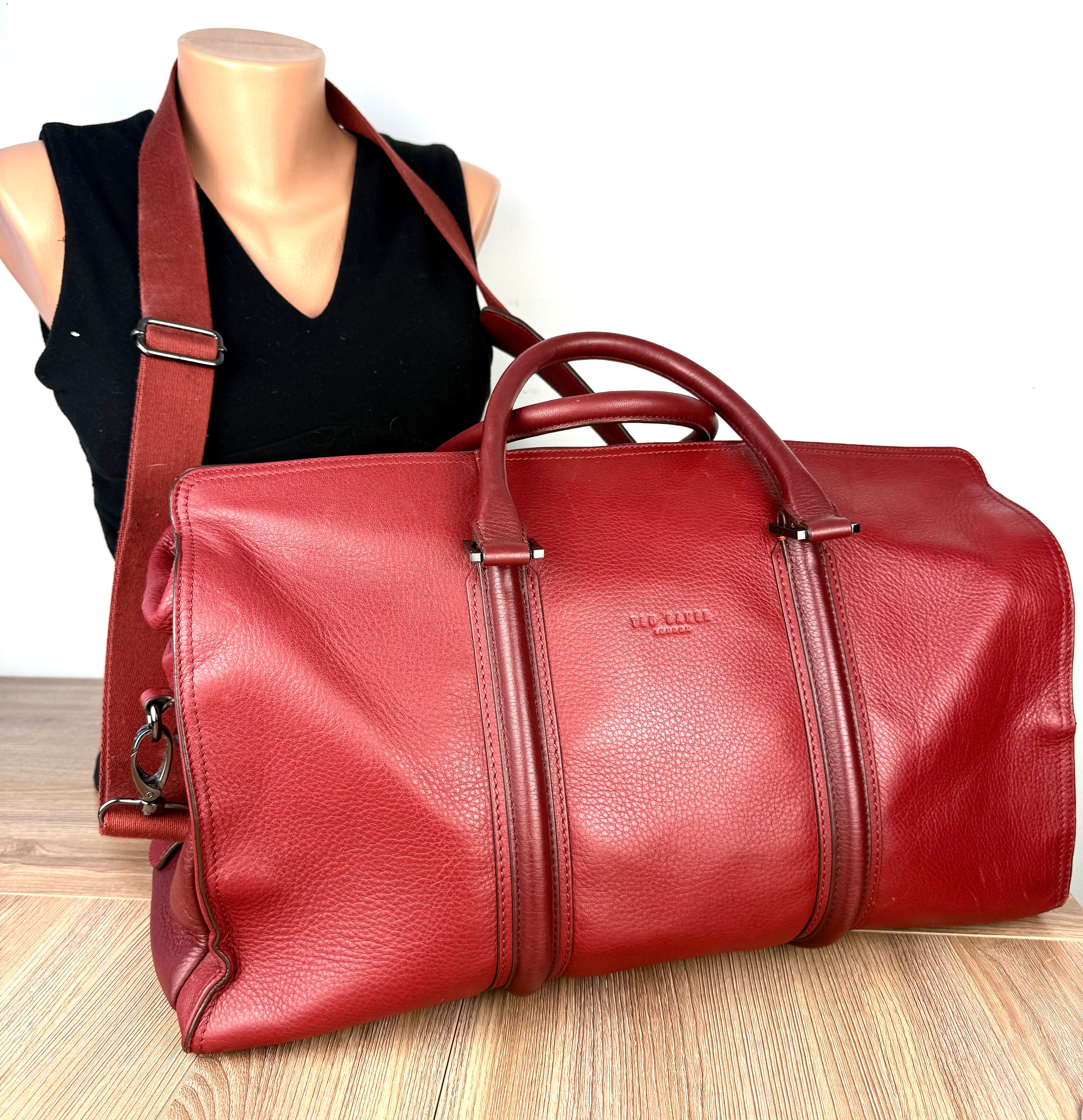 Ted Baker London red pebbled leather weekender duffel bag with adjustable shoulder strap displayed on mannequin.