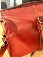 Ted Baker red leather travel duffel bag showing pebbled leather texture and structured design showing mark on the back