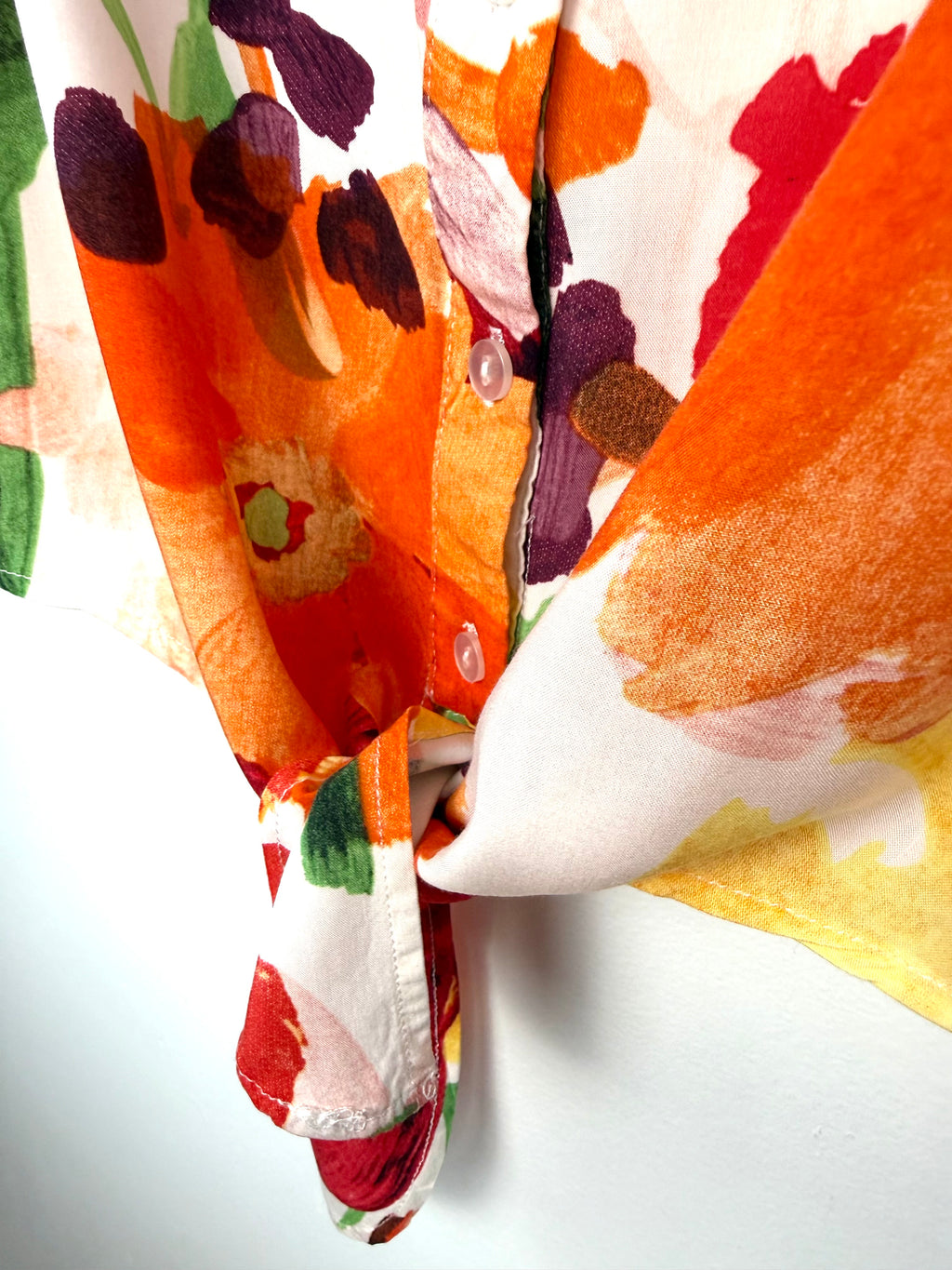 tie detail on Cleo tie-front V-neck floral blouse in bold painterly orange red and green botanical print