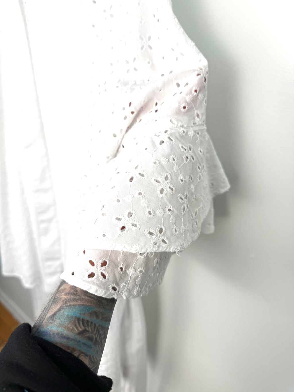Tiered ruffle sleeve detail on white eyelet kimono, feminine boho sleeve with scalloped embroidery.