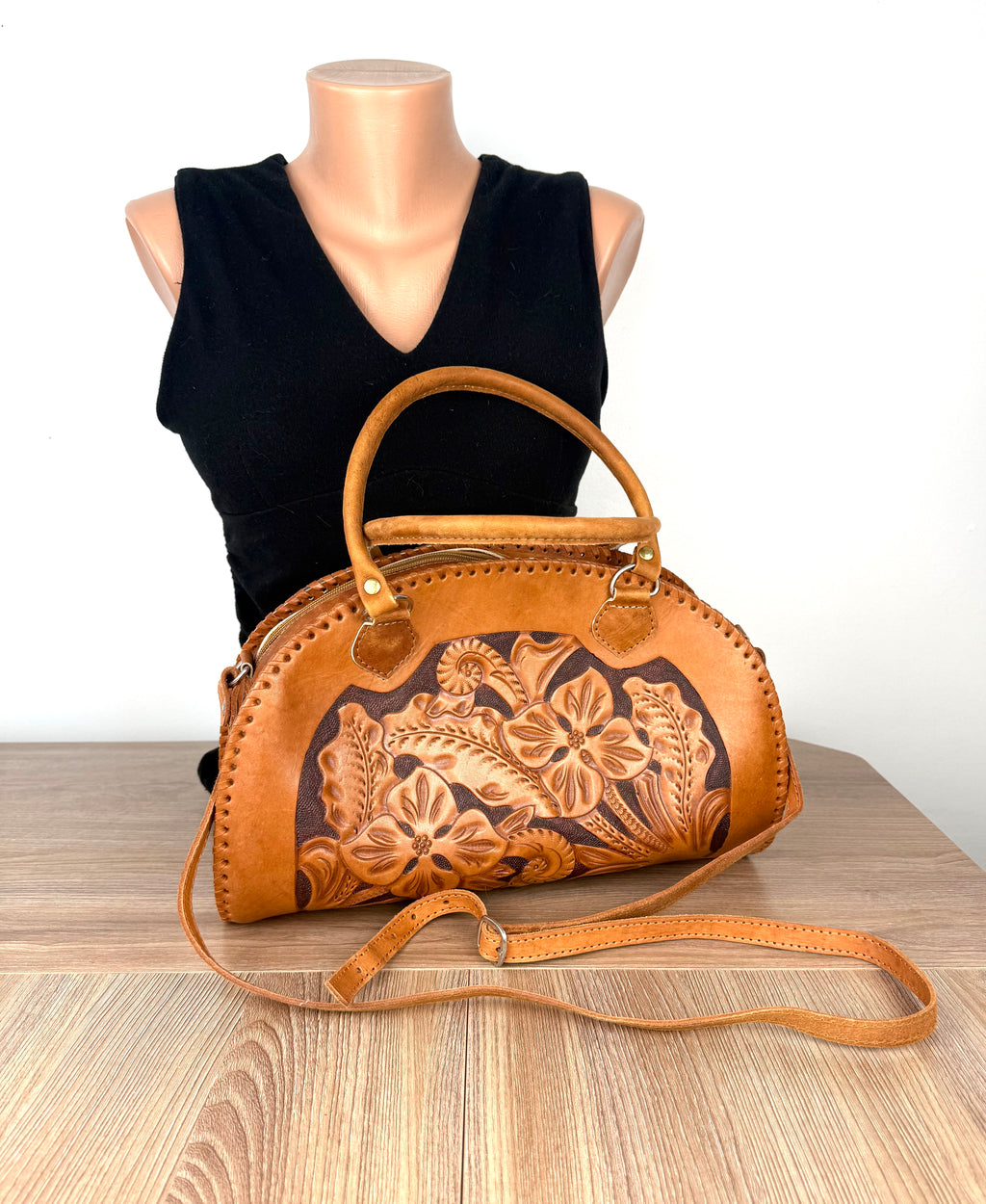 Vintage tan hand-tooled leather dome handbag with floral embossed front panel displayed on mannequin