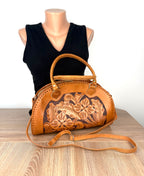 Vintage tan hand-tooled leather dome handbag with floral embossed front panel displayed on mannequin