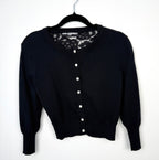audrey hepburn style cardigan with pearl buttons and lace back detail  on hanger
