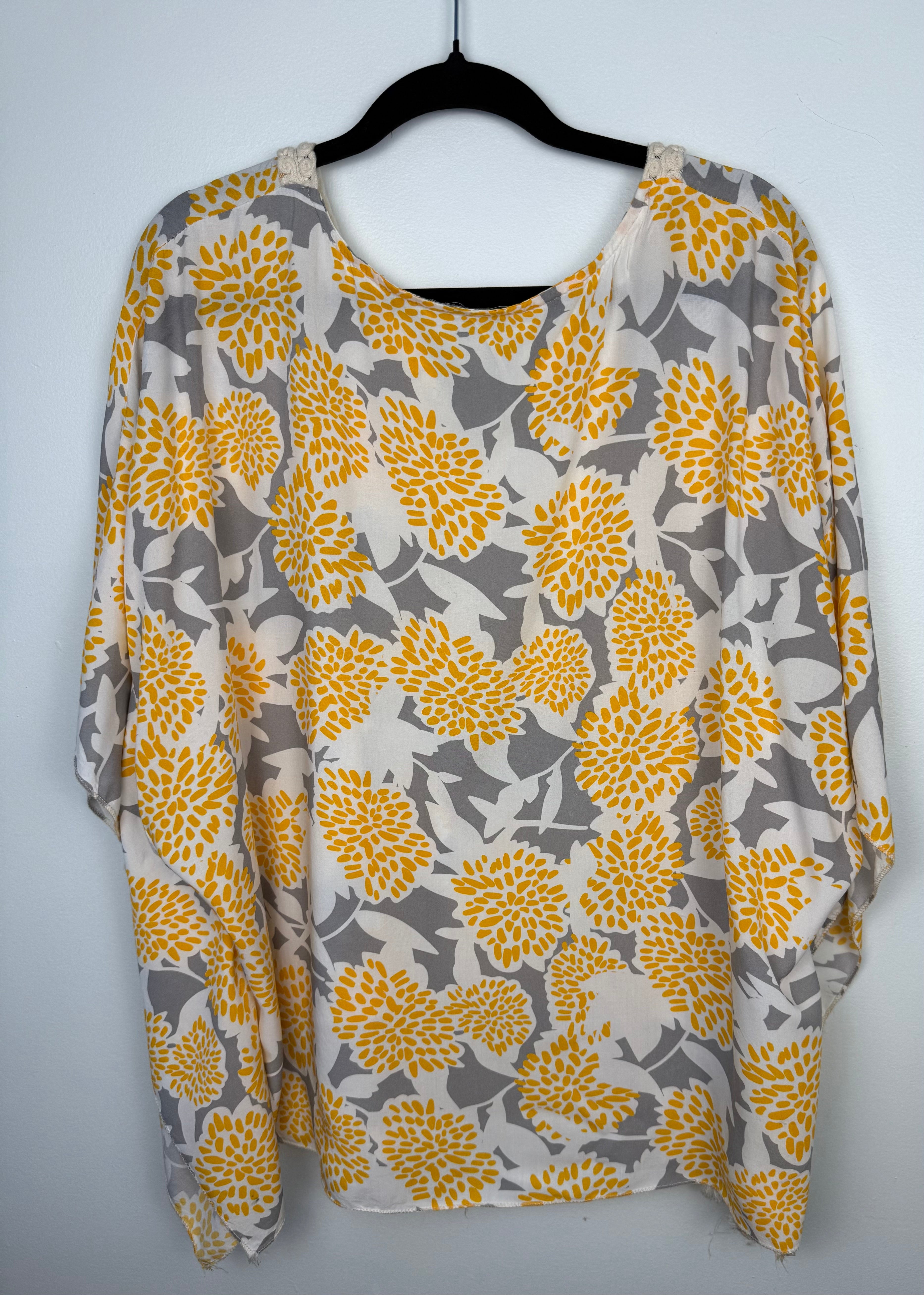 back of Made in Italy Boho floral kaftan top with yellow and cream print, crochet V neckline, and tassel hem, lightweight Italian viscose blouse on hanger