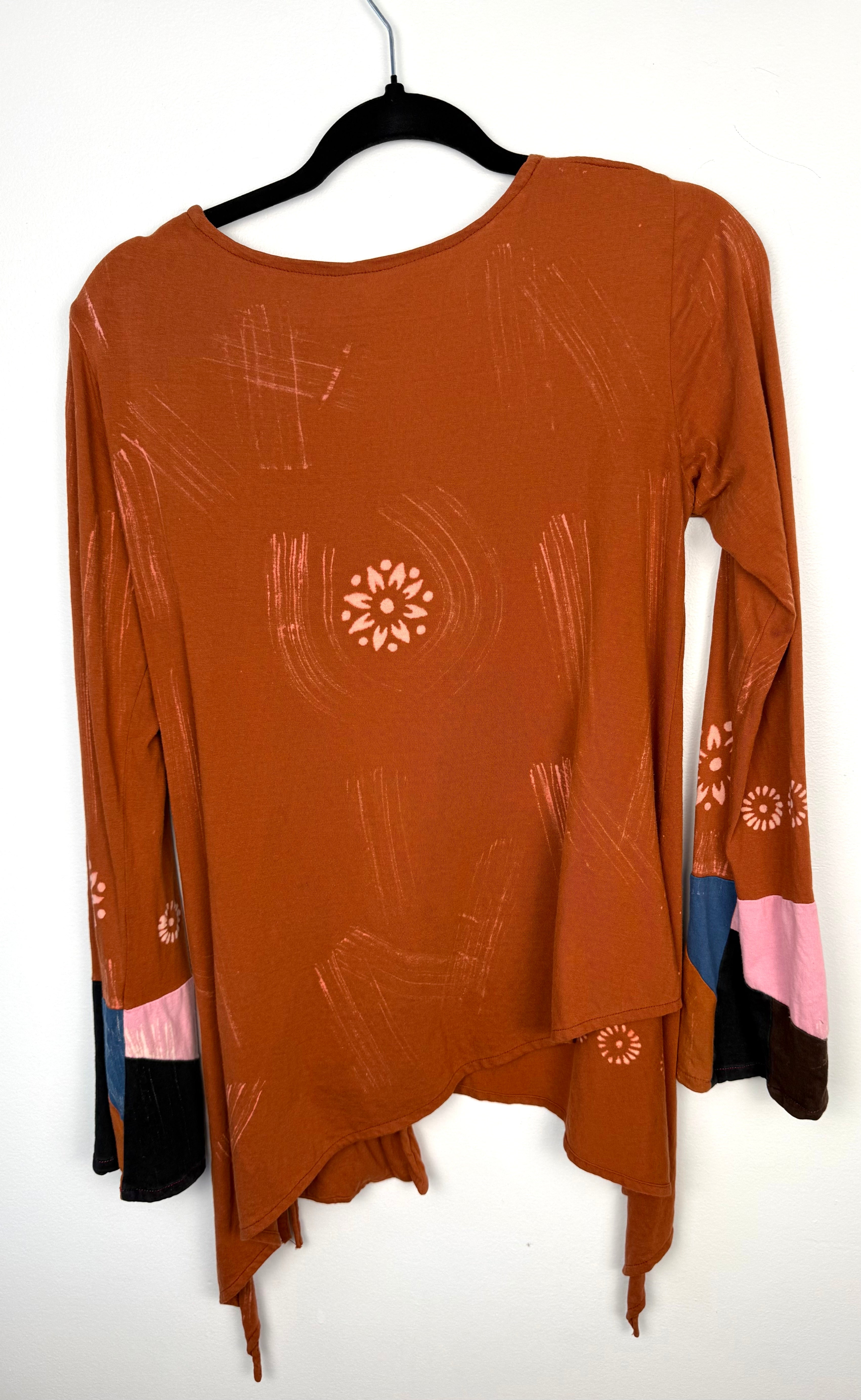 back of Tye dye boho artsy unique asymmetrical top in burnt orange   on hanger