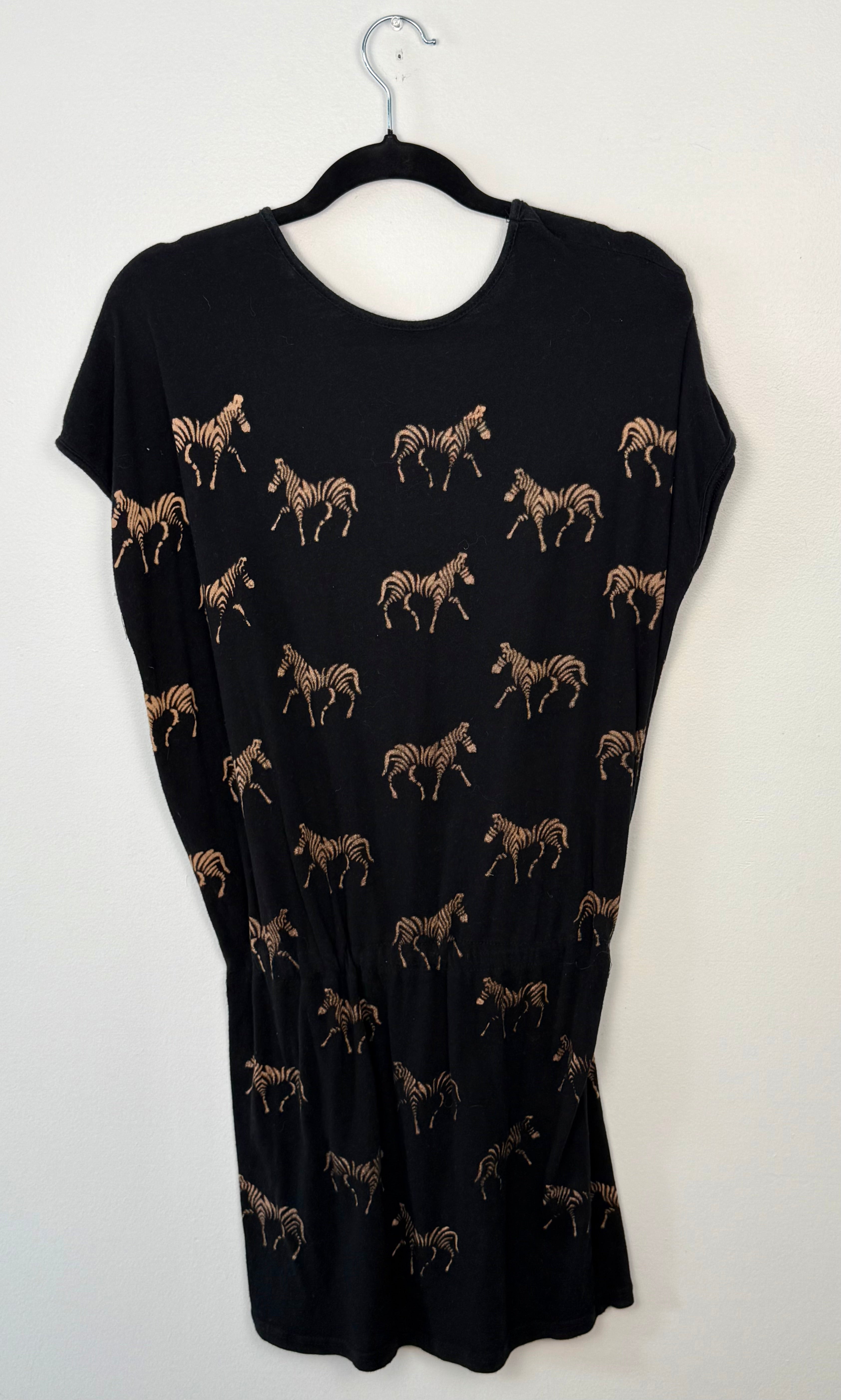 back view of black dress with zebra pattern on a hanger against a white background