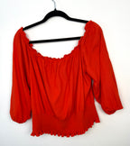 back view of Melanie Lyne orange peasant blouse on hanger