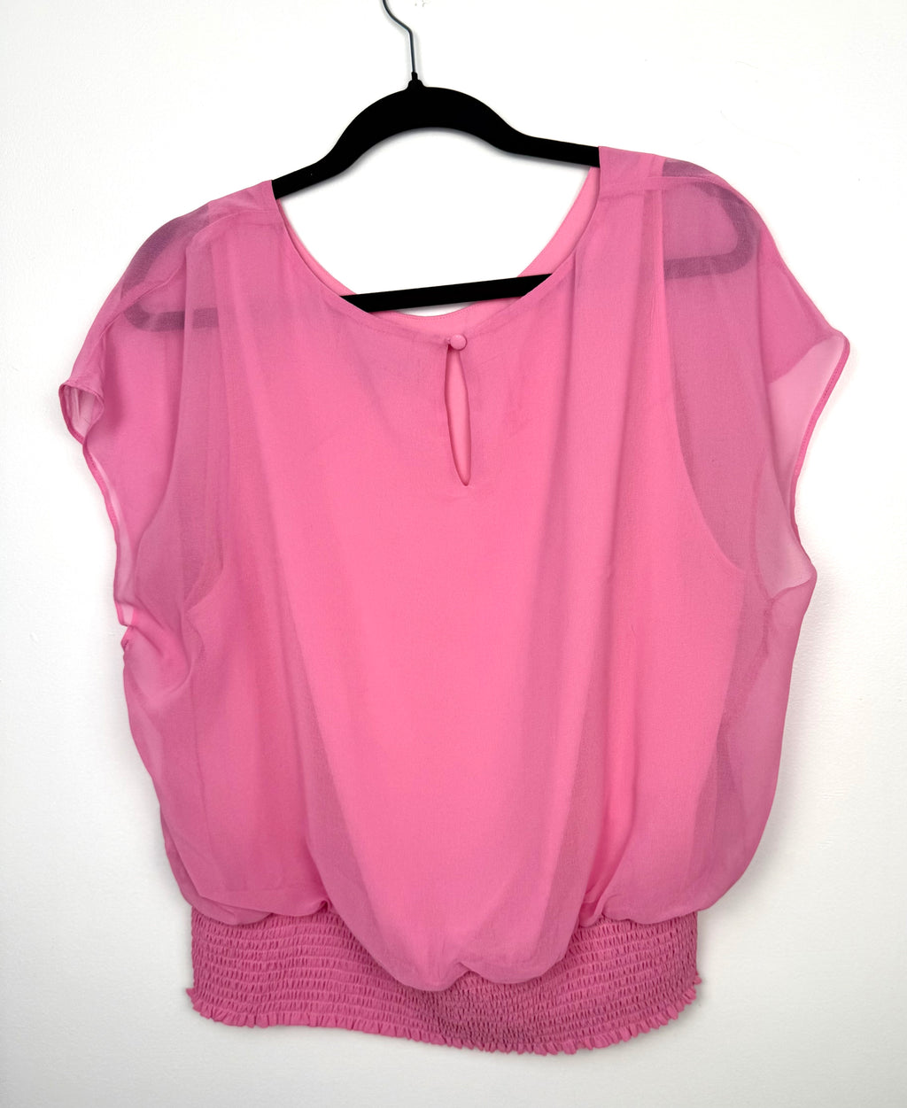 back view of Melanie Lyne pink chiffon blouse with smocked waist and flutter sleeves on hanger