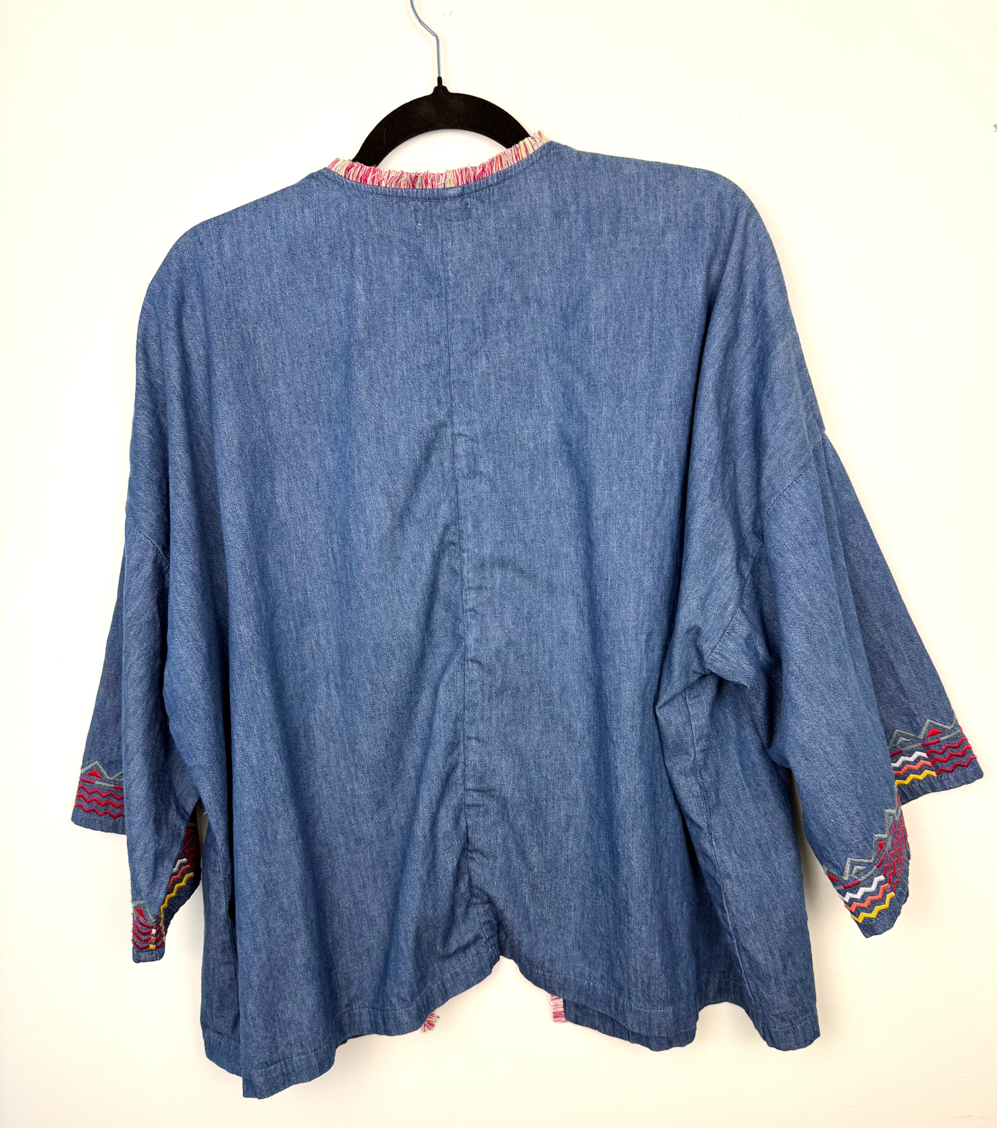 back view of lightweight chambray jacket women on hanger showing southwestern patterned cuff detail 
