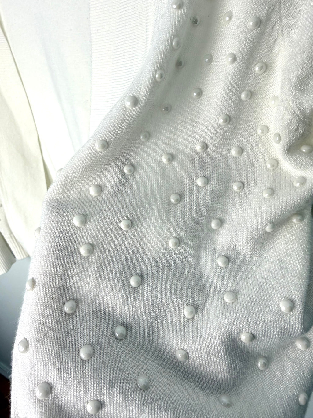 close up of pearl beading embellishment on feminine ivory cardigan sweater
