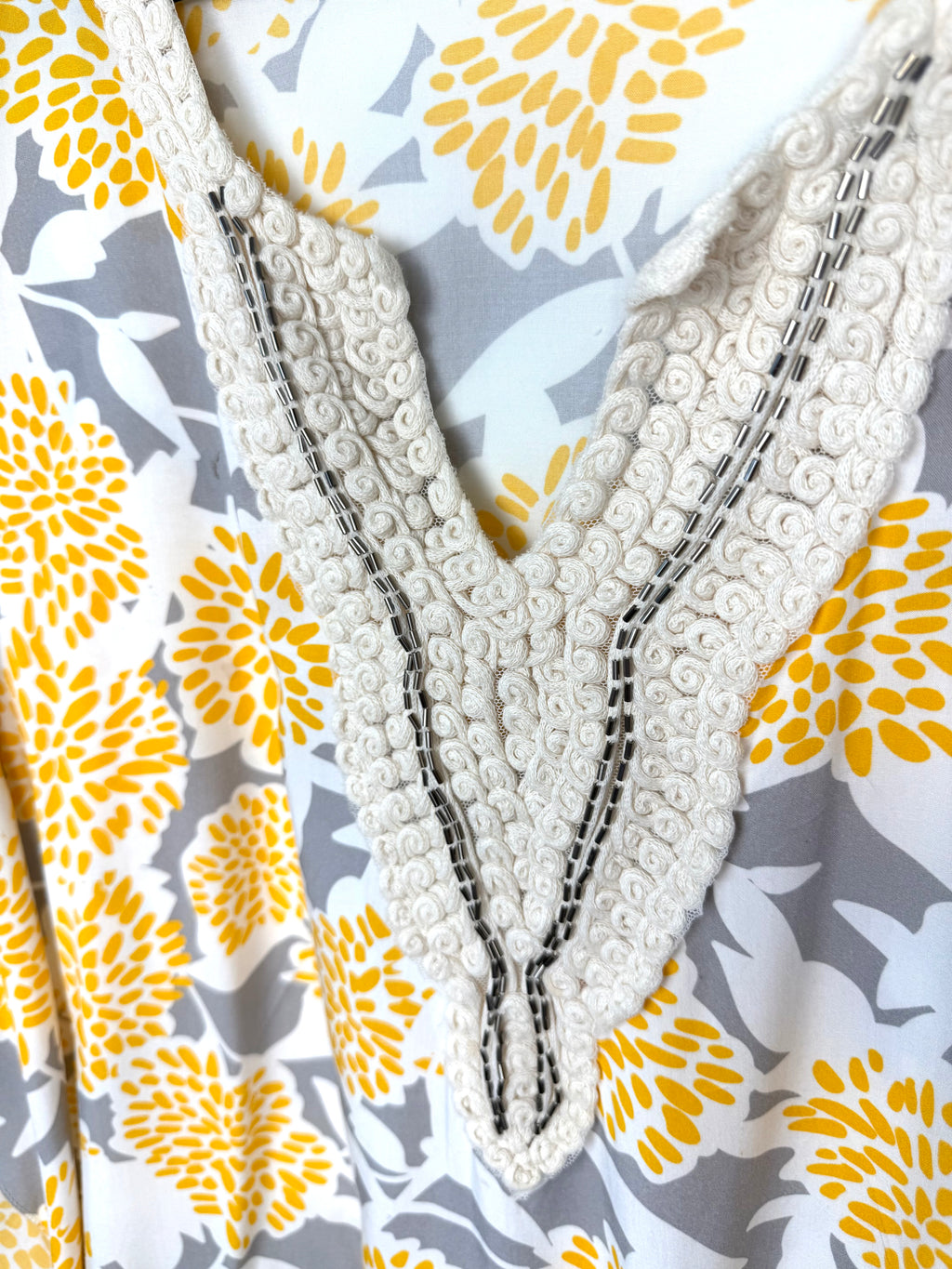 collar detail on Made in Italy Boho floral kaftan top with yellow and cream print, crochet V neckline, and tassel hem, lightweight Italian viscose blouse