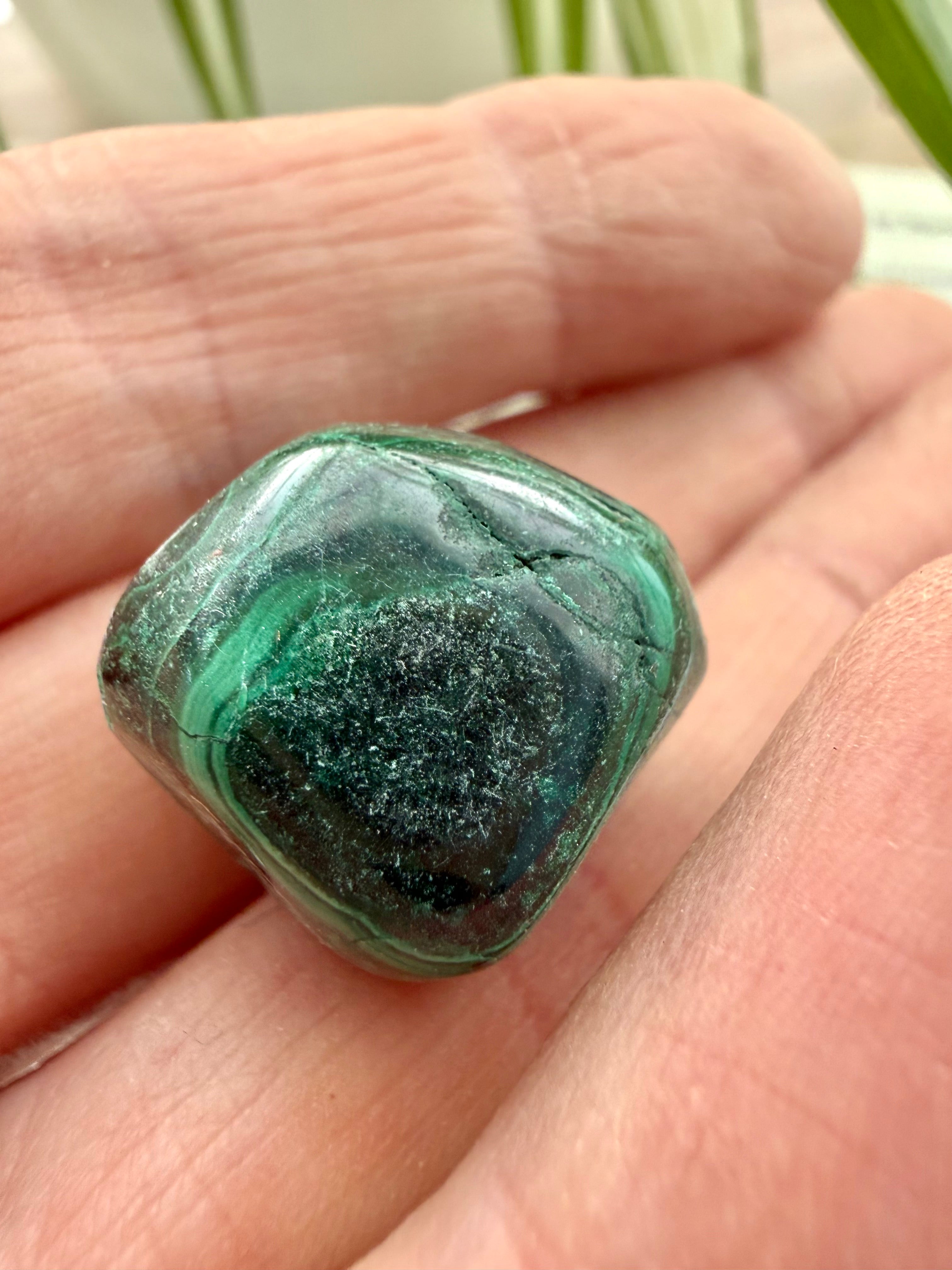 malachite  stone held in a hand with a blurred natural background