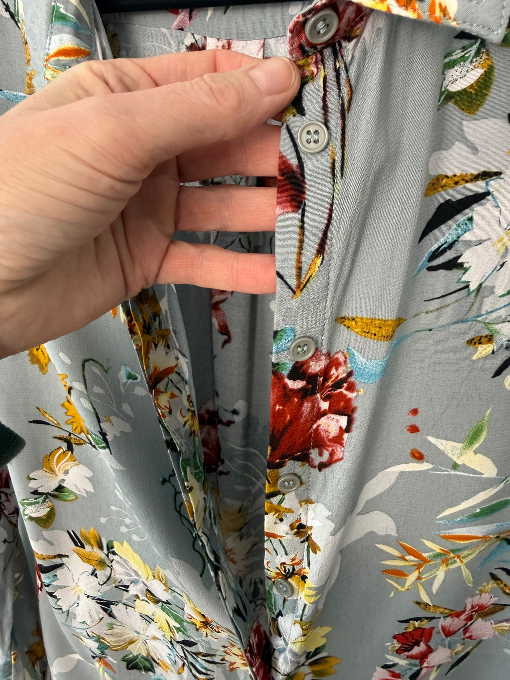 Hand holding a folded fabric with floral pattern on a matching fabric background