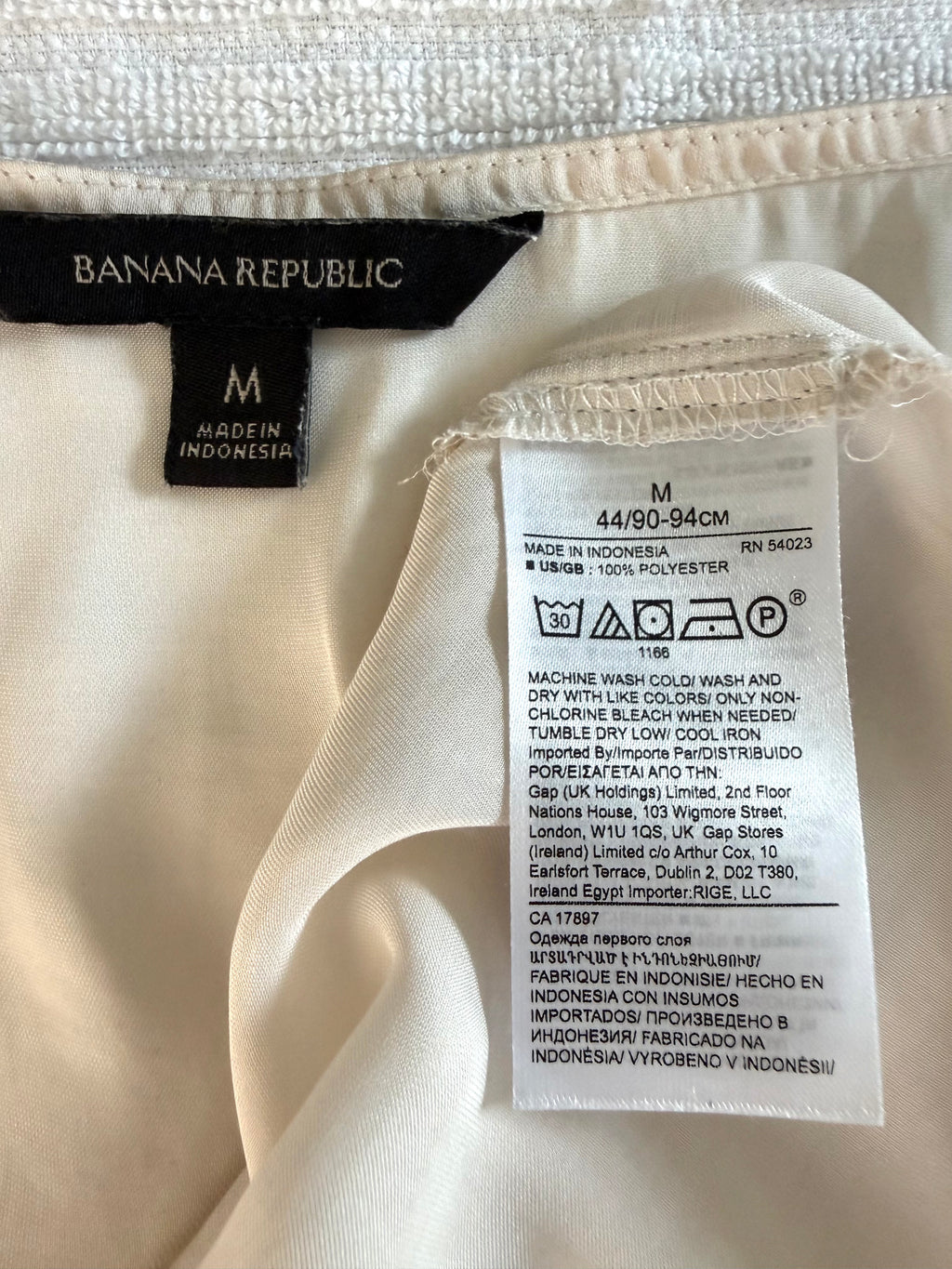 inside tags on Cream Banana Republic sleeveless blouse featuring a V-neckline, gathered shoulder detail, relaxed silhouette, and fluid drape throughout the body 