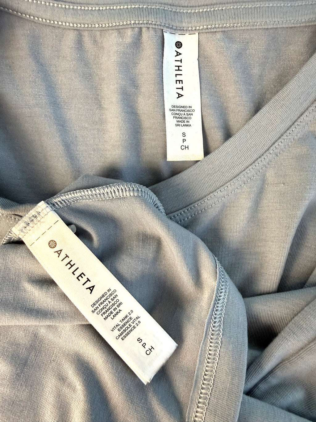 inside tags on Grey Athleta Vital Tank 2.0 sleeveless top, lightweight performance fabric, minimalist athletic layering piece