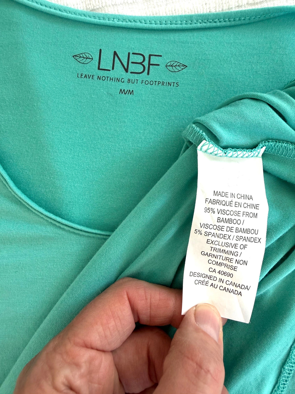 inside tags on Leave Nothing But Footprints Bamboo Tee | Size M in tiffany blue  showing 95% viscose from bamboo 
