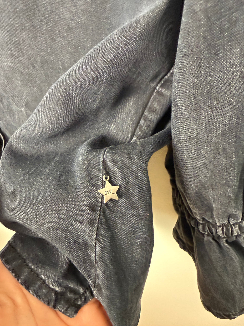 logo emblem on Sandwich Denim Studio Amsterdam charcoal 100% Tencel shirt with stunning hand-applied blue crystal collar embellishment and ruffle cuff detail at Blue Sparrow Shop